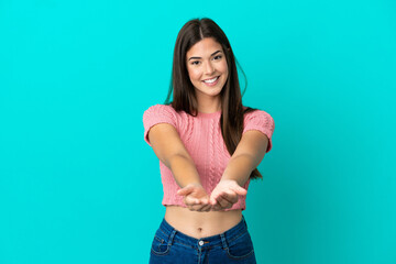 Young Brazilian woman isolated on blue background holding copyspace imaginary on the palm to insert...