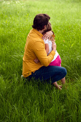 Fototapeta premium Loving Father Cuddling Young Daughter As They Walk Through Field Together