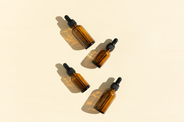 Bottles of dark amber glass with essential, lotion, serum on a beige background. Natural SPA organic cosmetic. Layout of the beauty salon branding. Flat lay, top view.