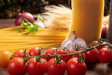 Italian pasta (macaroni), spaghetti, tomatoes, olive oil, cheese and spices on rustic wood, selective focus.