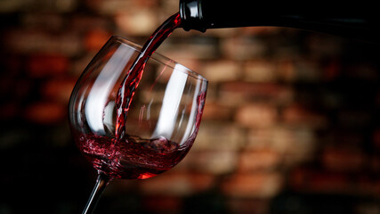 Freeze motion of red wine pouring into glass. - obrazy, fototapety, plakaty