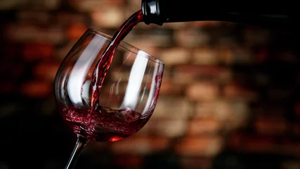Rolgordijnen Freeze motion of red wine pouring into glass. © Jag_cz
