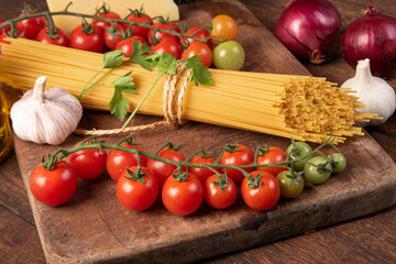 Italian pasta (macaroni), spaghetti tied with sisal string, tomatoes, olive oil, cheese and spices on rustic wood, selective focus.