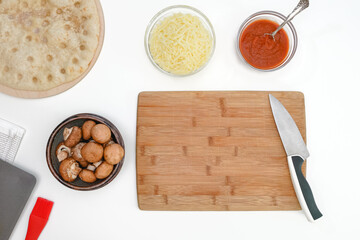 Pizza with mozzarella and crimini mushrooms recipe, ingredients close up on kitchen table, flat lay