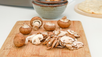 Crimini mushroom slices close up on wooden cutting board, preparation process, recipe