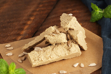 Sunflower halva on parchment paper on a wooden background with a blue napkin. Natural vegan product. Rustic style. Top view. Flat lay.