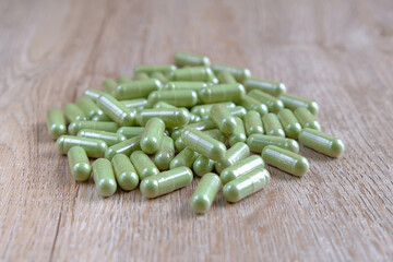 Andrographis Paniculata, Green Chiretta, herbal supplement, or natural herbal pills for detox, prevent, and immunity support in disease pandemic time. packed in the capsules on a wooden background.