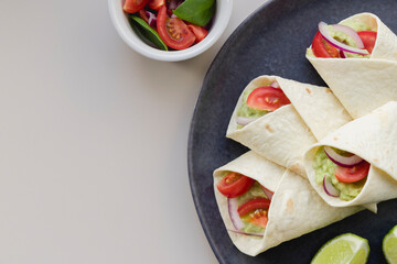 Grill roll of flatbread stuffed with avocado, tuna, tomato and onion on the blue plate. Delicious lunch, snack, fast food, healthy food.
