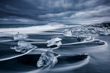 Majestic pieces of the iceberg sparkle on black sand. Location place Jokulsarlon lagoon, Iceland, Europe.