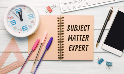 SUBJECT MATTER EXPERT - an inscription on a notebook on a table with office supplies.