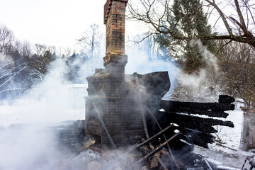Smoke on the ashes, brick chimney in smoke after a fire in a wooden building