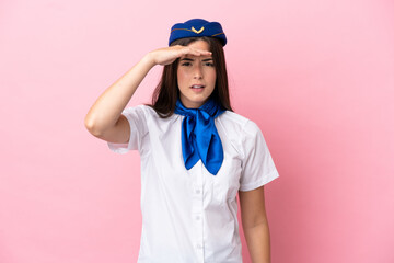 Airplane stewardess Brazilian woman isolated on pink background looking far away with hand to look something