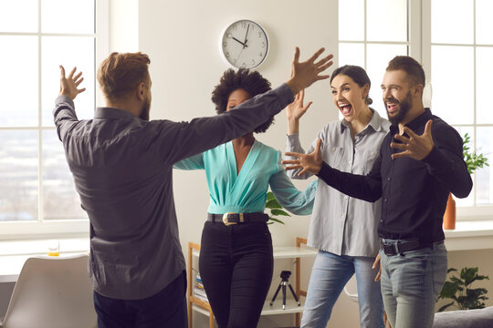 Having Fun Reunion. I'm Back. Long Time No See. Happy Man Spreading Arms Wide Open To Hug Friends He Missed So Much. Group Of Funny Men And Women Excited To Meet Coworker Who Returned From Far Away