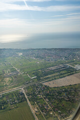 Land view through the airplane window. Fields, roads, rivers from a bird's eye view. Porthole. Look out the window of a flying plane. Top view of the ground