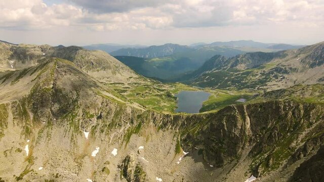 Aerial video of a mountain range shot from a drone while flying backwards, picking altitude. Footage was made from a drone at lake Bucura, in Hunedoara county, Romania.