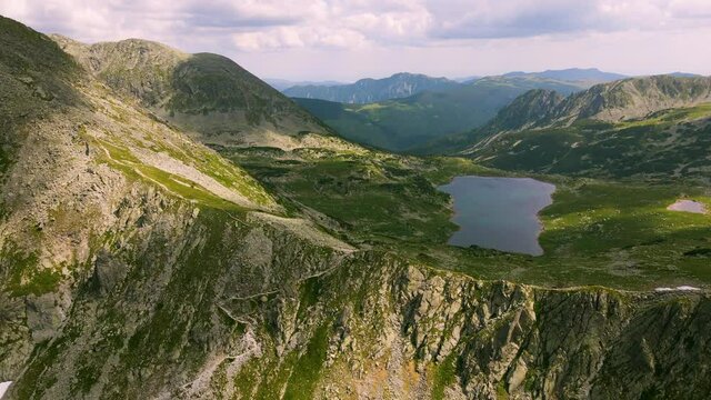 Aerial video of a mountain range shot from a drone while flying backwards, picking altitude. Footage was made from a drone at lake Bucura, in Hunedoara county, Romania.