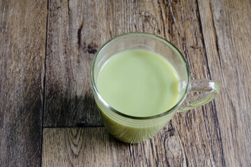 A cup of hot matcha milk tea on a wooden table