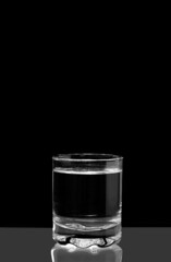 Clear water in a glass. Full glass of water on a black background. Black and white photo. Concept. Photo