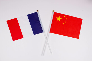 Flag of France and flag of China crossed with each other on a white background. Isolated. The image illustrates the relationship between countries. Photo for news and articles on the media
