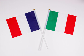 Flag of France and flag of Italy crossed with each other on a white background. Isolated. The image illustrates the relationship between countries. Photo for news and articles on the media