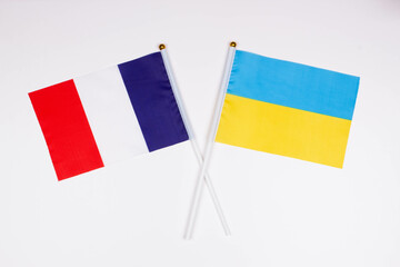 Flag of France and flag of Ukraine crossed with each other on a white background. Isolated. The image illustrates the relationship between countries. Photo for news and articles on the media