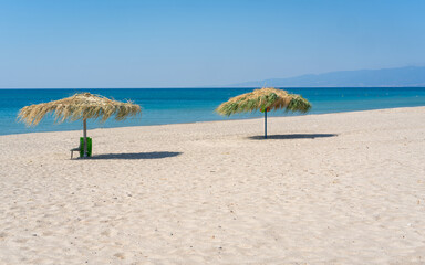 Two beach umbrela on sandy beach, mediterranean sea, Calabria Italy.