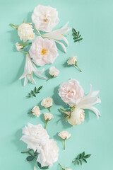 Creative summer composition made of rose and lily flowers on pastel mint background. Beautiful floral layout. Nature concept. Top view. Flat lay