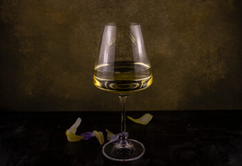 a glass of white wine on a long thin leg with exotic flower petals