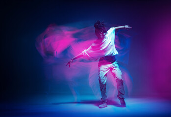 Stylish dancing modern girl moving in colorful neon studio light. Long exposure. Copy space - obrazy, fototapety, plakaty