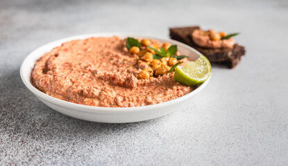 Roasted red pepper hummus garnish with mint and lime. Mashed chickpeas with red bell pepper, lime and mint. Vegetarian snack.