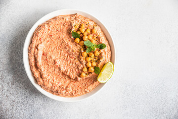 Roasted red pepper hummus garnish with mint and lime. Mashed chickpeas with red bell pepper, lime and mint. Vegetarian snack. Top view.