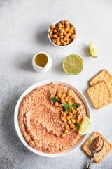 Roasted red pepper hummus garnish with mint and lime. Mashed chickpeas with red bell pepper, lime and mint. Vegetarian snack. Top view.