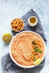 Roasted red pepper hummus garnish with mint and lime. Mashed chickpeas with red bell pepper, lime and mint. Vegetarian snack. Top view.