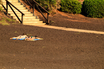 Two girls sunbathing at Lastre Beach in Portman village on a sunny day