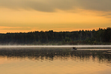 Fototapeta na wymiar people on a boat float on the lake at dawn
