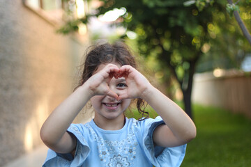 Smiling kid showing her love with gesture. Focus on eye.