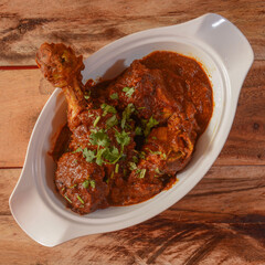 Chicken masala made of indian spices served in a bowl over a wooden rustic background. selective focus
