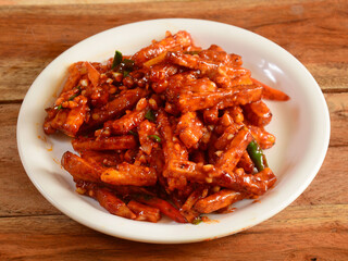 Sticky honey chilli potatoes in a spicy sauce, sesame seeds, It is indo-chinese cuisine dish. Authentic asian food. served in a white plate over a rustic wooden table. selective focus