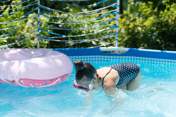 Kid use goggles in outdoor pool in summer, swimming