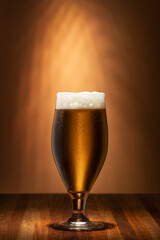  Cold Craft light Beer in a glass with water drops and foam on a wooden table in the pub. Beer close up. 