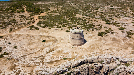 Aerial view of the round tower of Cape Barbaria, southwest of Formentera in the Balearic Islands, Spain - Bare landscape of Cabo Berberia with dramatic cliffs diving into the Mediterranean Sea