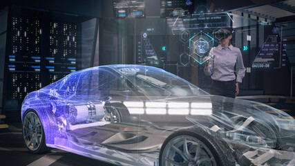 Automotive Female Professional Engineer working on design of Electric Car using Futuristic Augmented Reality Headset with Holographic Technology. High-tech facility. Electric car chassis.