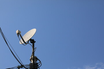 青空をバックに立つ衛星放送のパラボラアンテナ