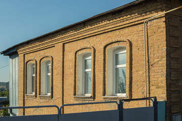 Facade of ancient brick house with new plastic windows