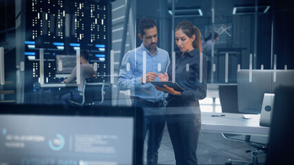 Professional Male and Female Engineers Working in High Tech Research Lab with Data Servers using Computers and Tablets showing Data and Graphs.