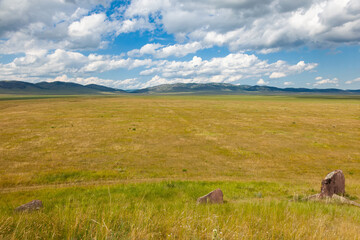 Obraz premium Stones in the Khakas steppe. Picturesque clouds over the hills of Khakassia, Russia.