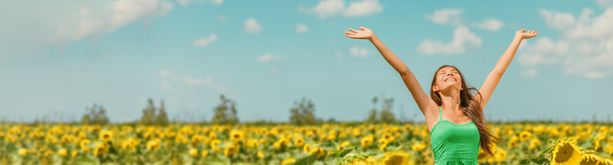 Spring happy woman with open arms walking in sunflower field enjoying free nature landscape banner panoramic. Asian girl relaxing breathing clean air outside. - obrazy, fototapety, plakaty