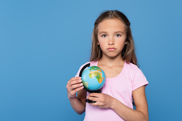 Upset kid with globe looking at camera isolated on blue