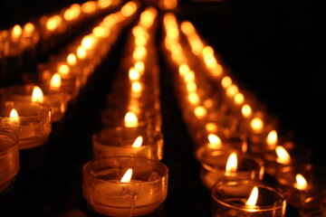 candles lighted lined up inside a church dark background