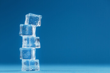 Cubes of melting ice tower on a blue background.
